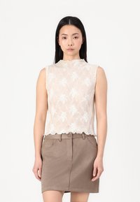 Top bege sem mangas com bordado floral e decote em forma de ondas, combinado com uma saia curta castanha com bolsos frontais e fecho de botão.