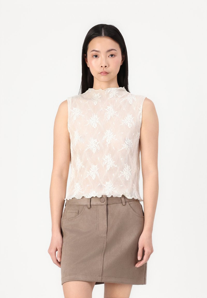 Top bege sem mangas com bordado floral e decote em forma de ondas, combinado com uma saia curta castanha com bolsos frontais e fecho de botão.