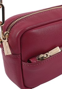 Bordeaux leren schoudertas met gouden hardware, dubbele ritscompartimenten, gladde textuur en gestikte details. Compact en functioneel ontwerp.