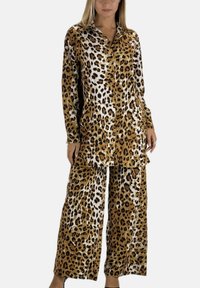 Conjunto de pijama con estampado de leopardo en marrón y crema, que incluye una camisa con botones y dos bolsillos delanteros, y pantalones de corte holgado. Textura suave.