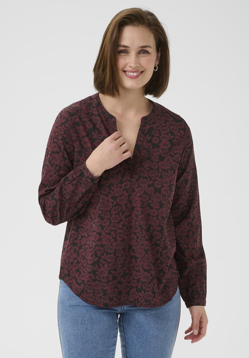 Langsleeve blouse in donker bordeaux met zwart bloemenpatroon, V-hals en ontspannen pasvorm. De stof lijkt lichtgewicht met een gladde textuur.