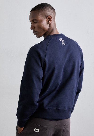 Sweat-shirt bleu marine avec des manches raglan et un détail d'astronaute brodé au dos, fabriqué dans un tissu doux et texturé.