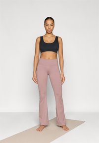Black athletic crop top and light pink flared yoga pants. The fabric appears smooth with a fitted design and high waistband. Plain textures.