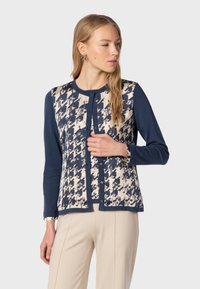 Navy blue cardigan with a cream and navy patterned front, featuring a round neckline, long sleeves, and button closure.