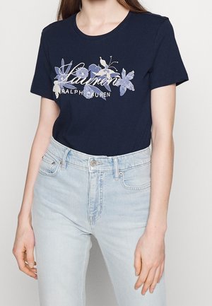 Námořnicky modré bavlněné tričko s květinovým potiskem a nápisem "Lauren Ralph Lauren". Kulatý výstřih, krátké rukávy, přiléhavý střih, ve spojení se světle modrými džínami.