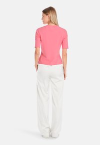 Fitted short-sleeve top in bright pink, paired with loose white cargo pants, showcasing a clean, minimalistic design.