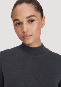 Dunkelgrauer Rollkragenpullover mit strukturiertem Rippmuster, enganliegendem Schnitt und taillierten Ärmeln. Glattes Material mit minimaler Verzierung.