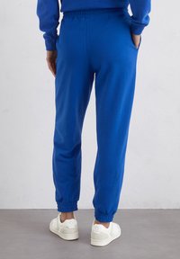 Blauwe sweatpants van een katoenmix, met een elastische tailleband en boorden, zijzakken en gedragen met witte sneakers.
