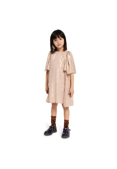 Robe courte à manches courtes rose pâle avec un motif texturé, associée à des chaussettes à motifs orange et noires et des chaussures bleu foncé avec des lacets orange.