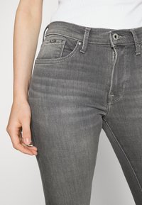Grå denimjeans med slim fit, med fem fickor, dragkedja och subtila blekningsdetaljer. En liten logotagg är synlig fram.