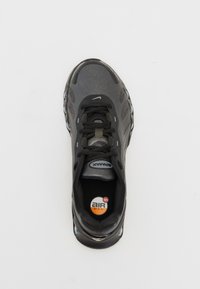 Basket noire Nike Air Max avec un dessus texturé, des lacets et un amorti visible, présentant un logo rond sur la semelle intérieure.