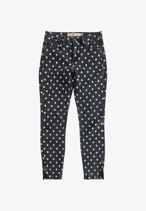 Zwarte skinny jeans met witte stippen, gulp met rits, riemlussen en ritsen bij de enkels.