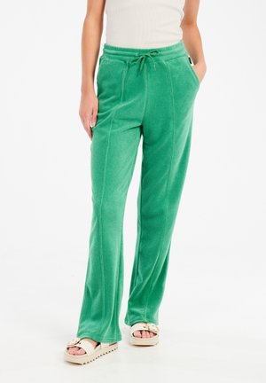 Pantalones de felpa verde con cintura ajustable, bolsillos laterales y diseño de pierna acampanada, que presenta detalles de costura vertical.