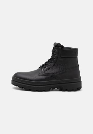 Bottines en cuir noir avec une finition texturée, bout rond, design à lacets, col rembourré et semelle en caoutchouc épaisse pour une meilleure adhérence.