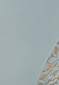 Tela azul claro con un panel de encaje texturizado a lo largo de un borde, con patrones florales que muestran detalles intrincados y un acabado suave.