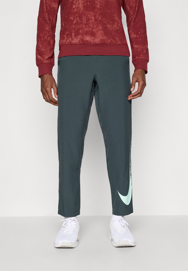Pantaloni sportivi Nike di colore verde scuro con un design affusolato. Presentano un logo di colore verde menta su un lato. Realizzati in tessuto morbido e traspirante.