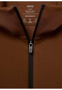 Felpa zip di colore marrone con zip e colletto neri. Il materiale è morbido e dalla trama liscia. L'etichetta mostra la taglia e le istruzioni per la cura.