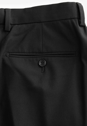 Pantaloni neri con una tasca posteriore dotata di un solo bottone nero, realizzati in un tessuto testurizzato, che presenta un design sartoriale.