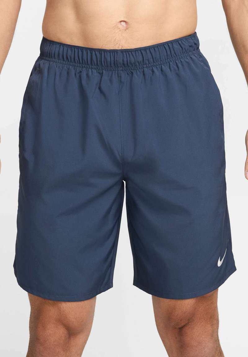 Bermudas deportivas azul marino hechas de una tela ligera, con una cinturilla elástica y un pequeño logo blanco en la parte inferior de la pierna izquierda.