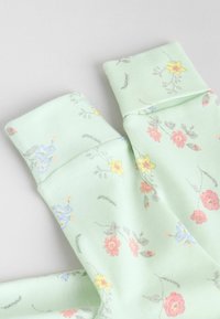 Chaussettes en coton vert clair avec un motif floral comprenant des fleurs roses, jaunes et bleues. Les bords sont côtelés et d'une texture douce.