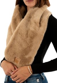 Scarf in pelliccia sintetica beige che si adagia attorno al collo, caratterizzato da una texture morbida e un piccolo tag in pelle con il logo di una corona.
