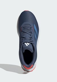 Scarpa da ginnastica navy con tomaia in mesh traspirante, suola intermedia bianca e dettaglio rosso sul tallone. Presenta lacci e logo con tre strisce bianche.