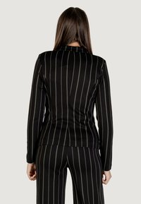 Černý pruhovaný blazer s vertikálními zelenými pruhy. Přiléhavý střih s dlouhými rukávy a jednoduchým límcem. Hladká textilie.
