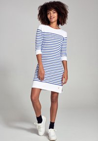 Abito a righe bianco e blu, con scollatura a barca, maniche a tre quarti e uno spacco laterale con un piccolo logo accentato.