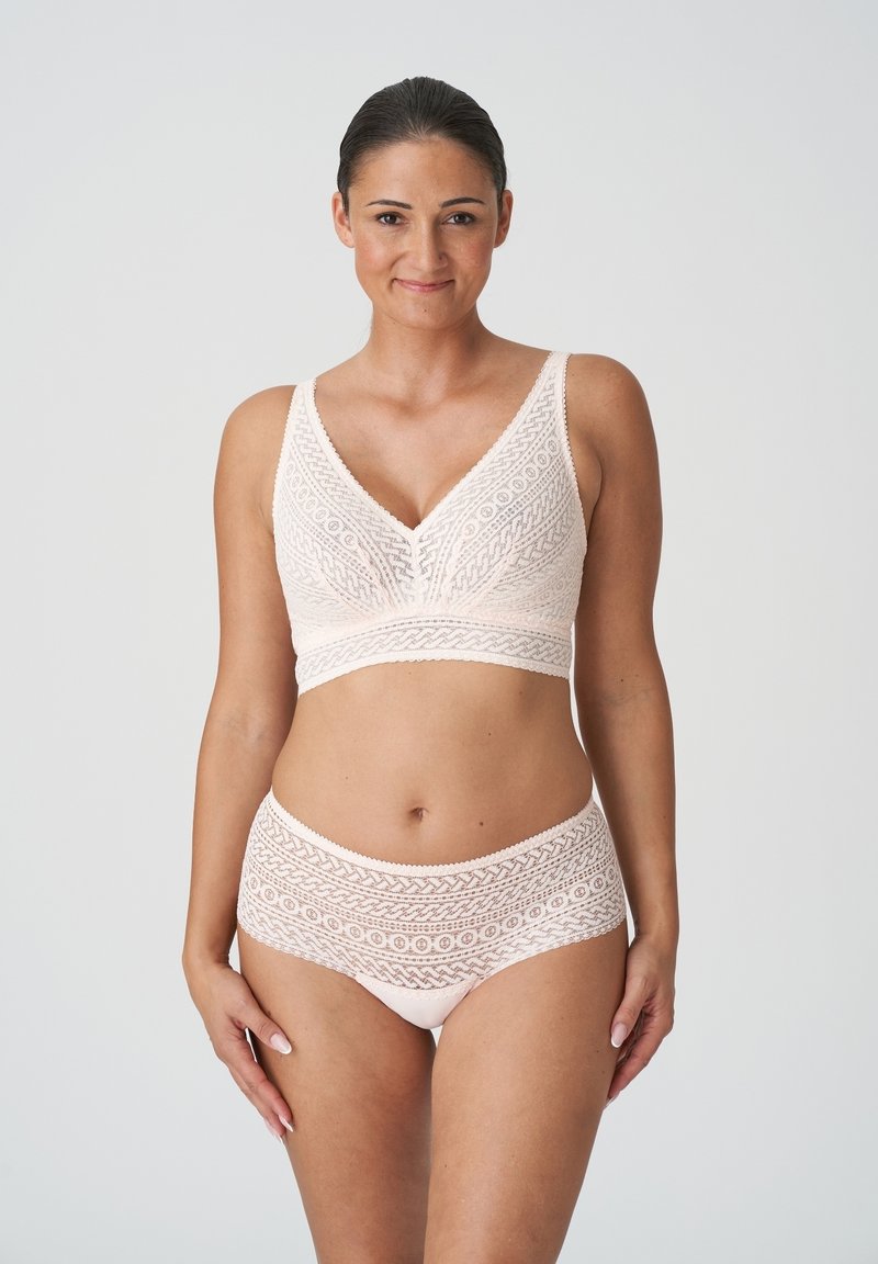 Lichtroze kanten bralette en bijpassende high-waisted slip, met ingewikkelde geometrische patronen en een zachte, textuurachtige afwerking.