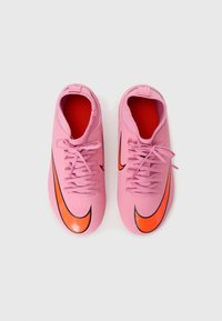 Rózsaszín Nike focicipők narancssárga pipa logóval, textúrált felszíni kialakítással, fűzős elejével és kontrasztos piros belső bélésével.