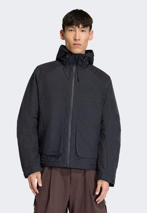 Schwarze Jacke mit Reißverschluss, Kapuze und zwei Vordertaschen. Verfügt über eine glatte Textur und ein minimalistisches Design. Dezentes Logo auf der Brust.