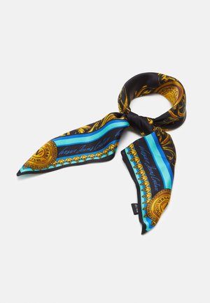 Musta silkkihuivi kultaisilla barokkikuviolla, sinisillä raidoilla ja Versace Jeans Couture -logolla, solmittuna löysään solmuun valkoisella taustalla.