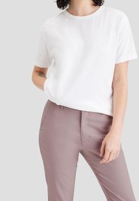 Vit kortärmad t-shirt med rund halsringning, tillsammans med ljus mauve slim-fit byxor. Släta tyger med en minimalistisk design.