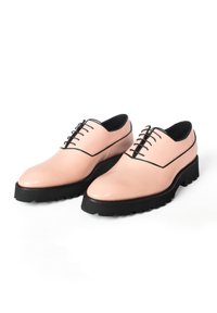 Lichtroze leren schoenen met een glanzende afwerking, zwarte veters en een dikke zwarte rubberen zool met robuuste profiel en zijdetails.