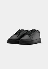 Zwarte synthetische lederen sneakers met platte veters, ronde neus, gestructureerde zool en subtiele gegraveerde logodetails. Over het algemeen een laag profiel ontwerp.