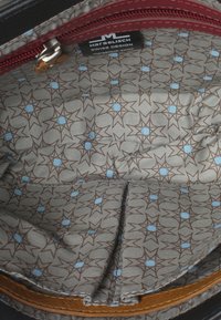 Interno nero di una borsa con una cerniera color bordeaux; presenta un motivo geometrico di stelle marroni e azzurro chiaro su uno sfondo grigio.