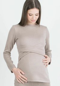 Maglietta premaman beige a maniche lunghe con una fascia in vita, realizzata in tessuto morbido, con scollo rotondo e maniche aderenti.