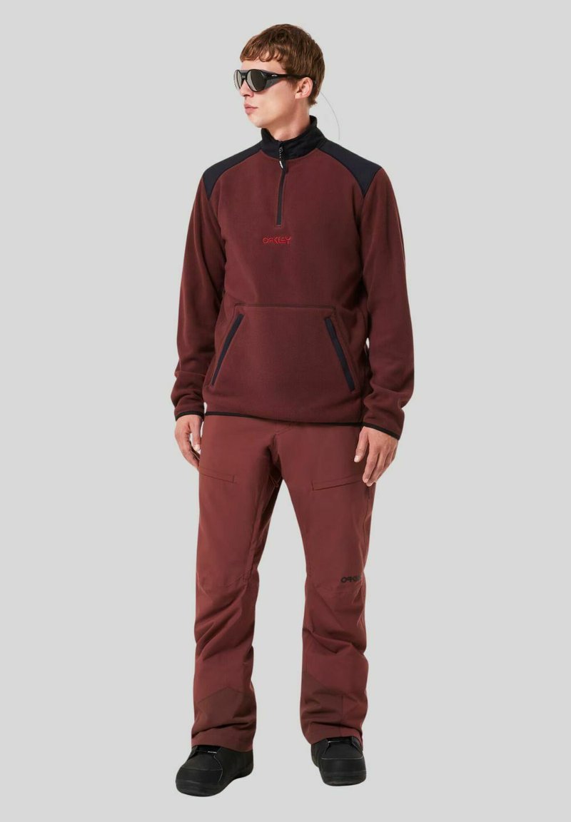 Men's maroon fleece pullover with a high collar and front zipper, paired with matching maroon pants. Includes pockets and dark accents.