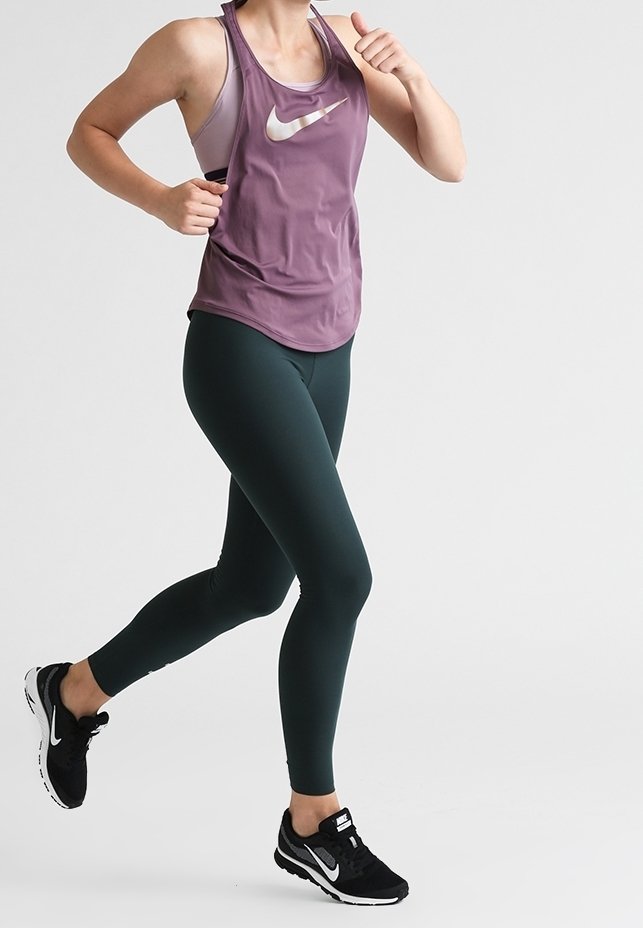 Top atletico viola senza maniche con logo Nike bianco, abbinato a leggings verde scuro e scarpe da corsa nere; design liscio e aderente.