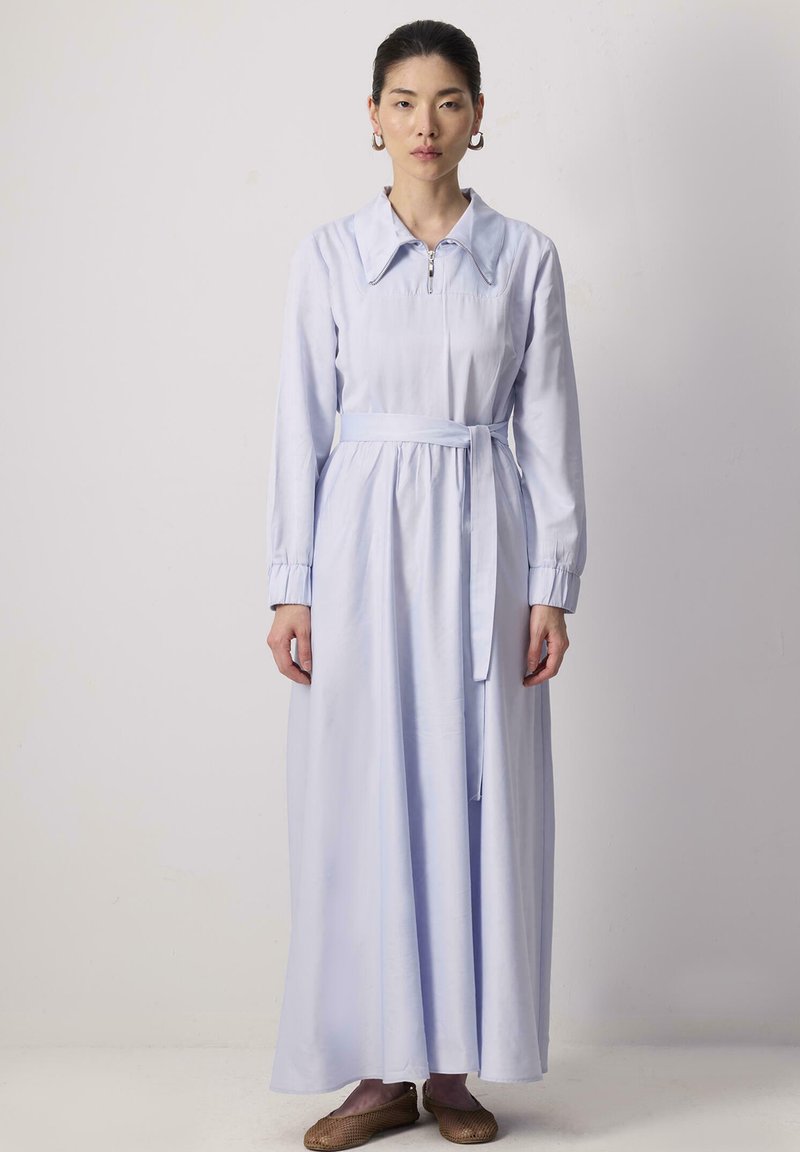 Robe à manches longues bleu clair avec un col, fermeture éclair à l'avant, poignets élastiques et une ceinture assortie à la taille.