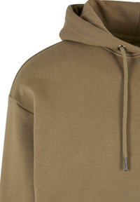 Felpa con cappuccio in un colore beige tenue, caratterizzata da un tessuto texturizzato, occhiello in metallo per il cordoncino e una vestibilità rilassata.