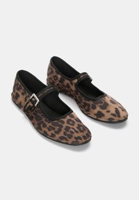 Chaussures plates à imprimé léopard avec une bride noire et un détail de boucle. Tige en tissu doux, bout rond et finition contrastante le long des bords.