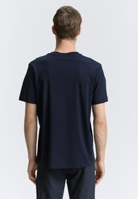 Camiseta de algodón azul marino con mangas cortas, cuello redondo y un corte regular. Textura suave con un detalle mínimo.