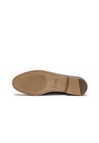 Suela de zapato azul marino con textura de goma antideslizante; presenta punta redondeada y un acento cosido a lo largo del borde. Tacón plano y acabado suave.