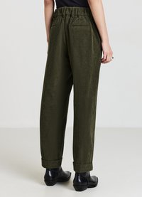 Grüne Cordhosen mit lockerer Passform, elastischem Bund und umgeschlagenen Bündchen. Verfügen über zwei Gesäßtaschen und eine strukturierte Oberfläche.