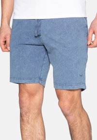 Shorts in denim azzurro chiaro con una texture sbiadita, vita con cordoncino e tasche laterali. Presentano un logo discreto vicino all'orlo.