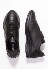 Sneakers in pelle nera con una texture liscia, punta arrotondata e design con lacci. Presentano una suola nera imbottita e un branding sottile.