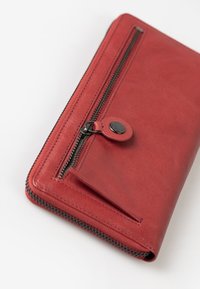 Rote Lederbörse mit Reißverschluss und Druckknopf, mit glatter Textur und kontrastierenden Stichdetails.