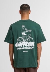 Green cotton t-shirt featuring a white graphic of a cyclist holding a coffee cup and text "CAFFEINE DEPARTEMENT" at the back.