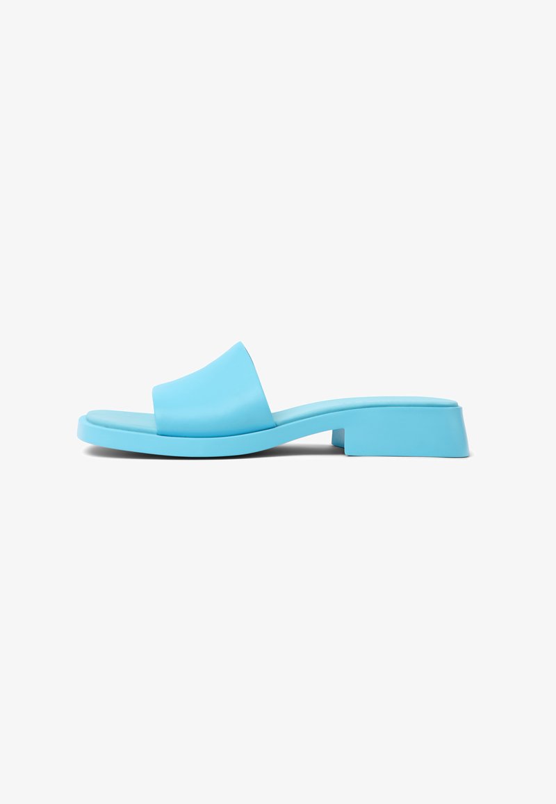 Infradito blu in plastica con una larga fascia, suola piatta e un tacco basso. Finitura liscia e lucida con un design minimalista.